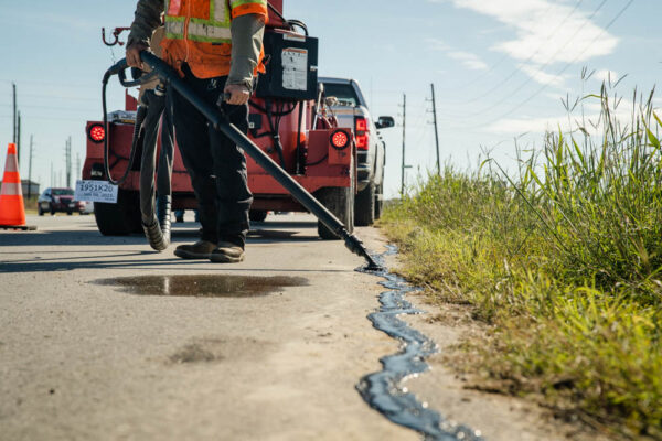 AAA Paving worker sealing the cracks in local road.